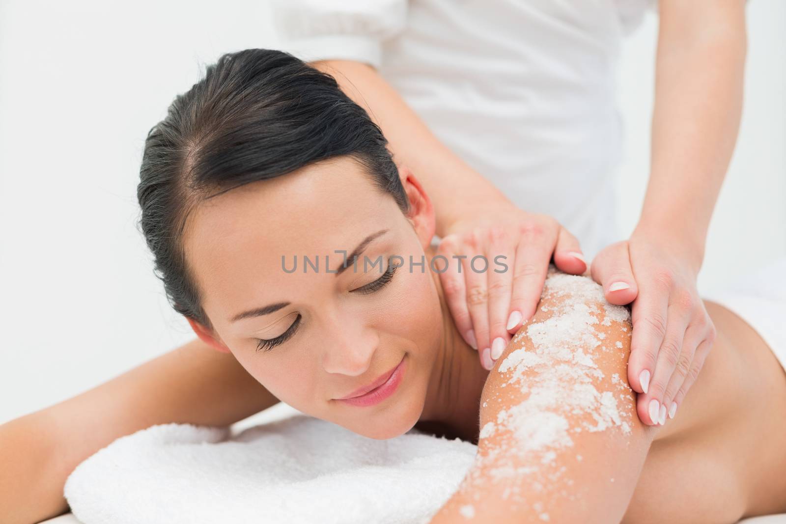 Peaceful brunette getting a salt scrub beauty treatment by Wavebreakmedia