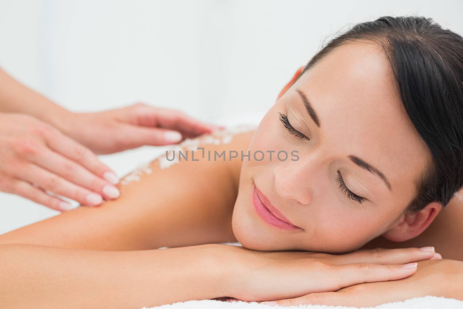 Peaceful brunette getting a salt scrub beauty treatment by Wavebreakmedia