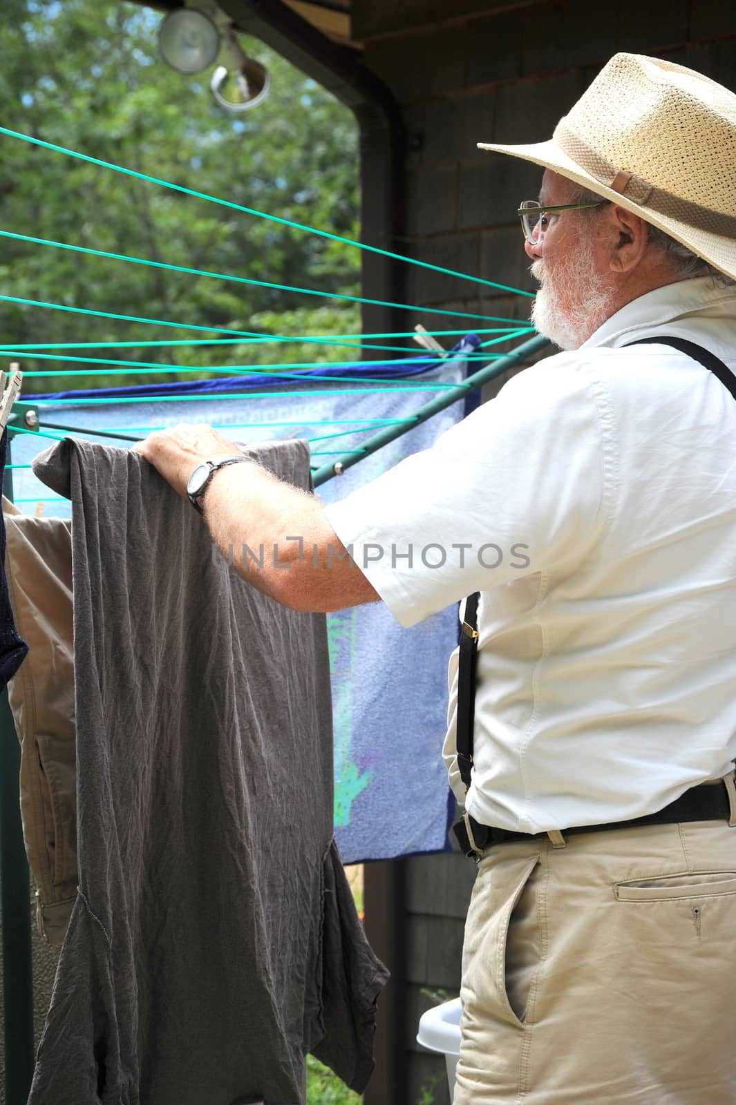 Country gentleman washing and line drying clothes outside.