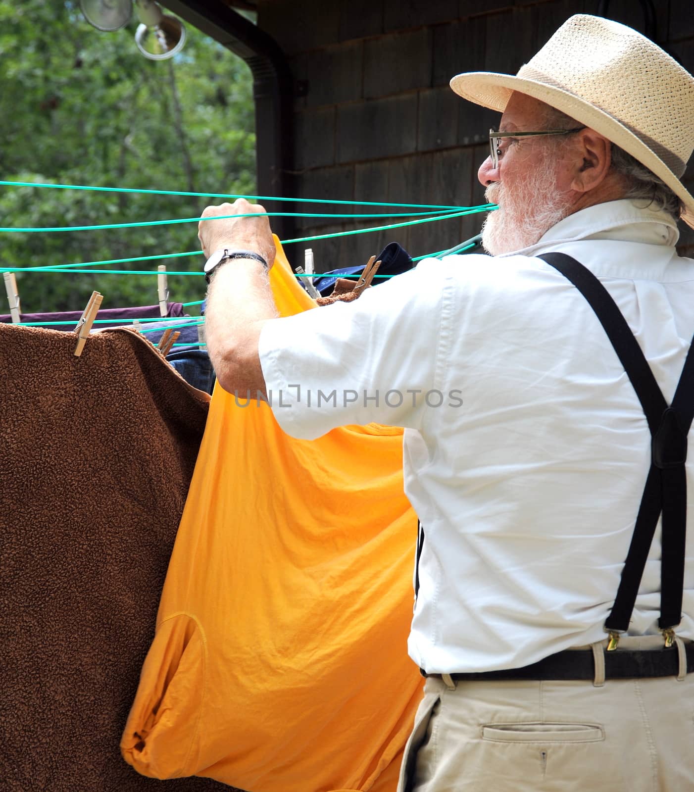 Country gentleman washing and line drying clothes outside.