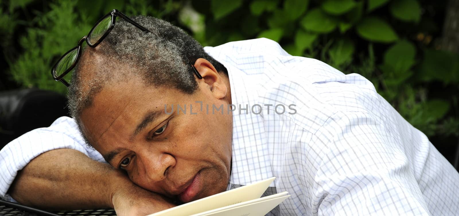 African american male writing on a table outdoors.