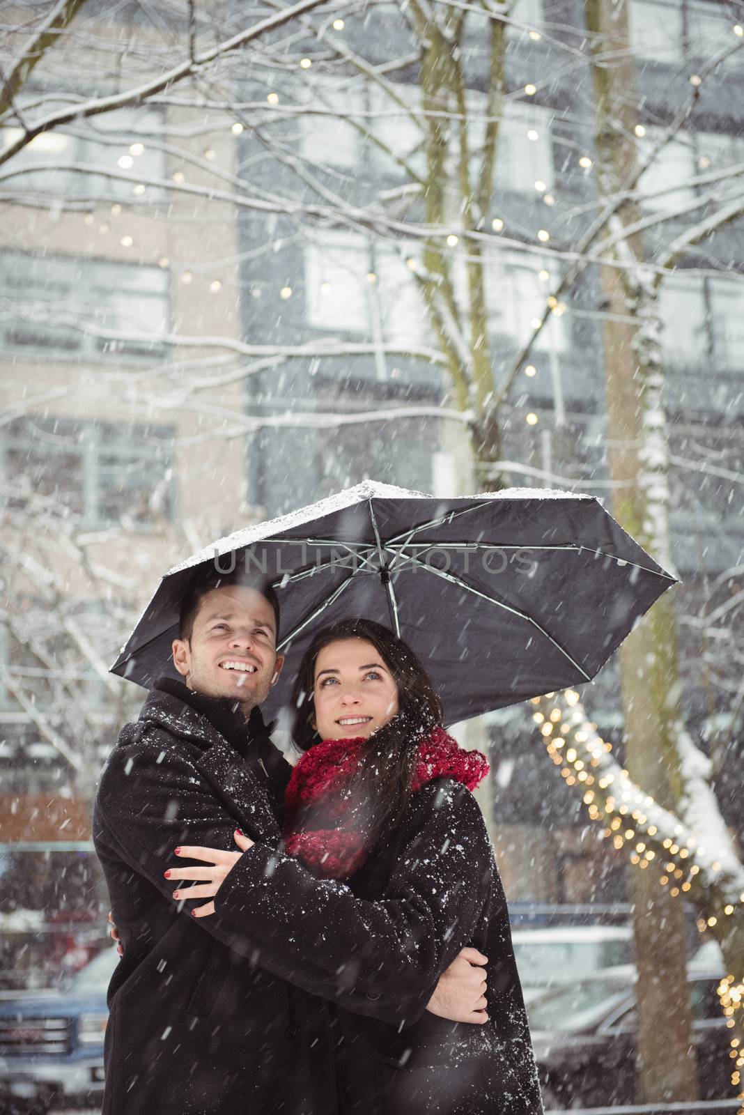 Romantic couple embracing in street during snowfall