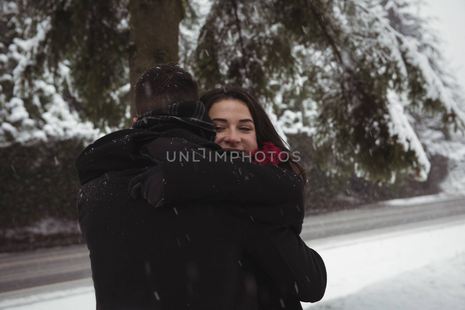 Romantic couple embracing in forest during winter