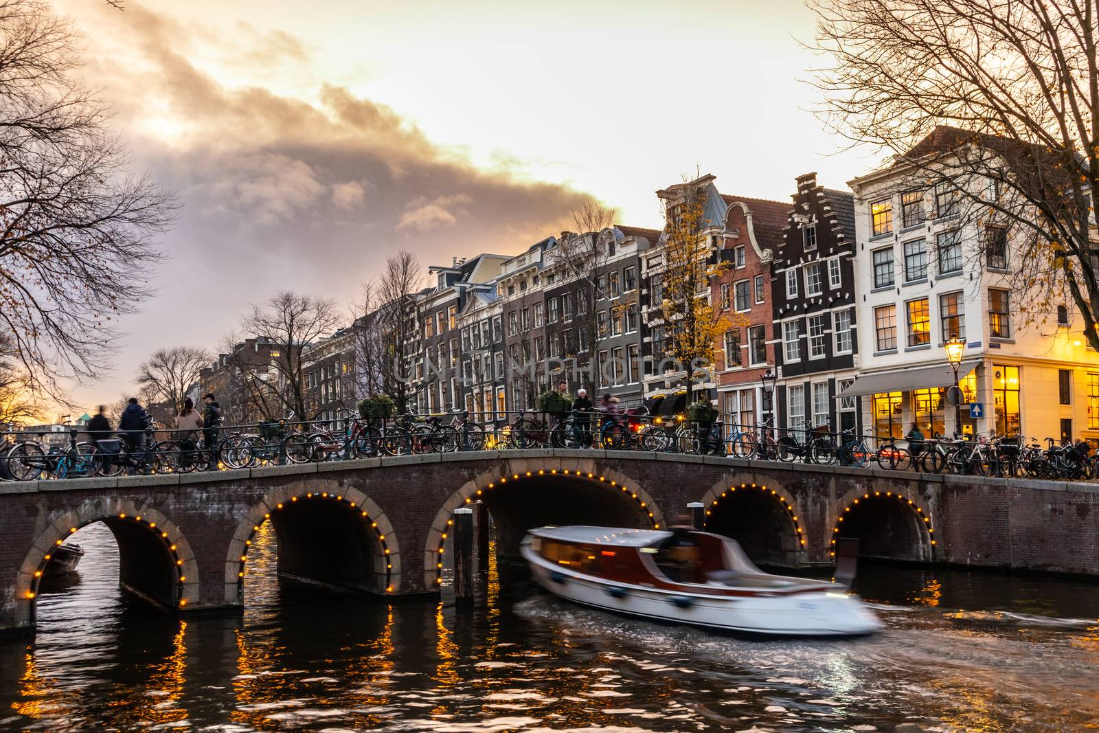 Amstedam, capital of Netherlands. Beautiful tranquil scene of city of Amsterdam at dusk. Bicycles along the street and on the bridge over the canal.