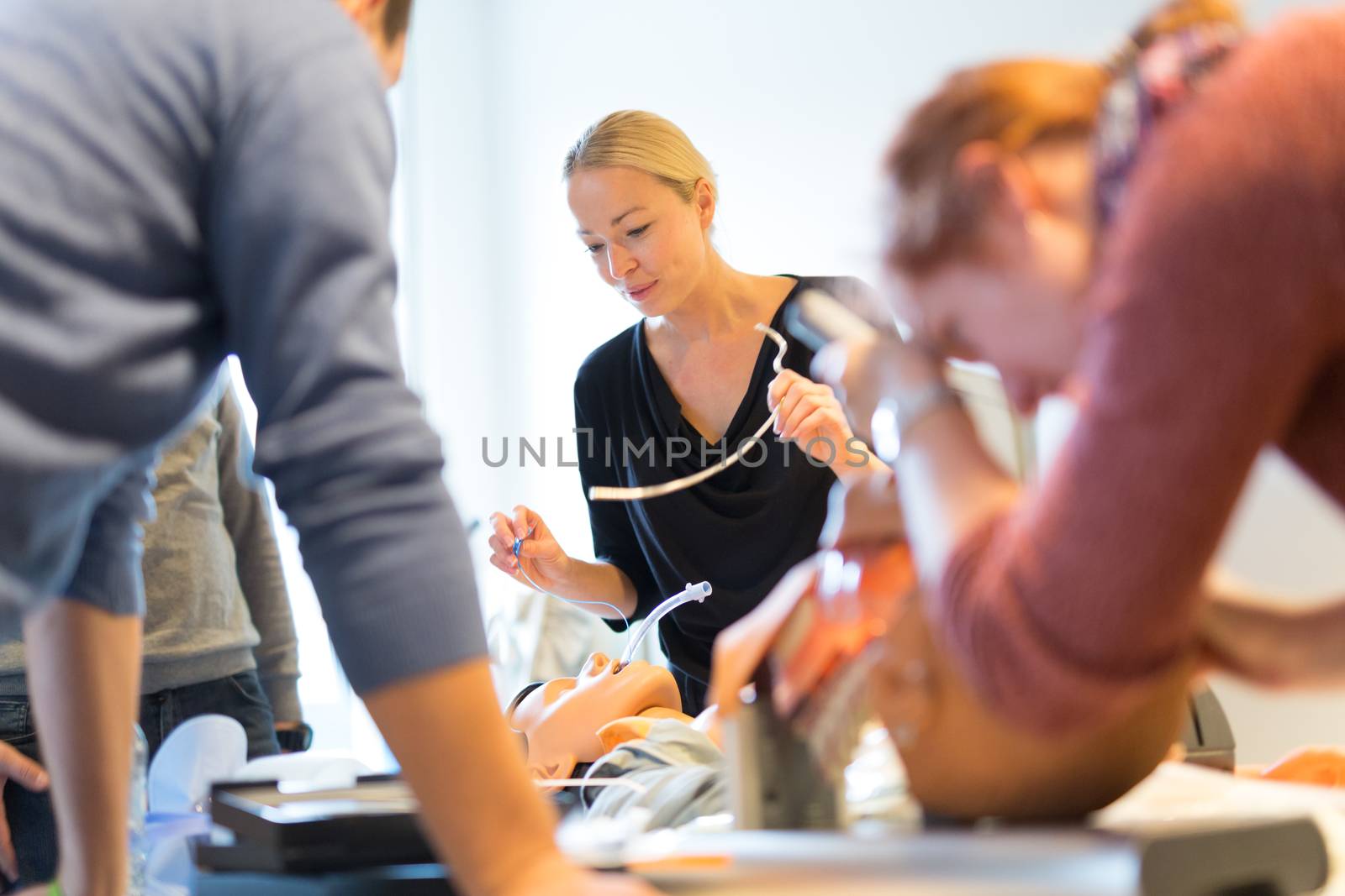 Medical doctor expert instructor displaying method of patient intubation on medical education training and workshop. Participants working in teams learning new medical procedures and techniques.