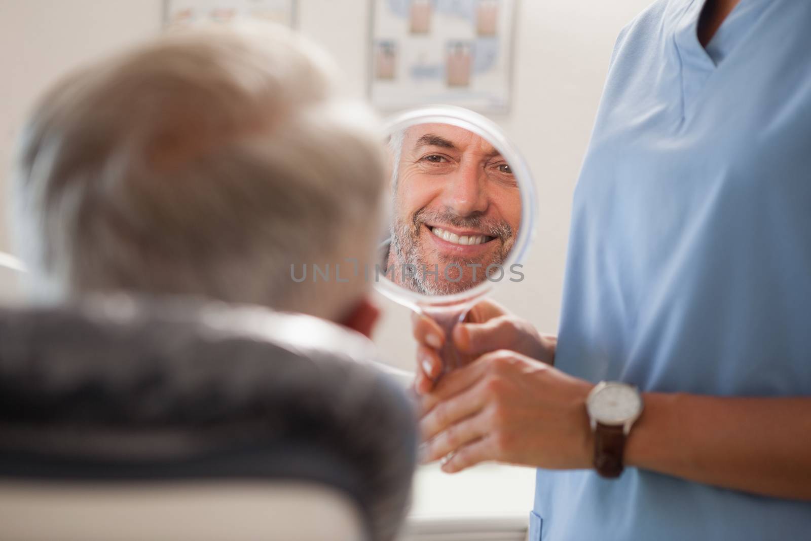 Dentist showing patient his new smile in the mirror by Wavebreakmedia