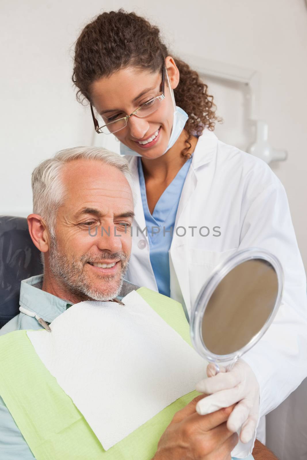Patient admiring his new smile in the mirror at the dental clinic