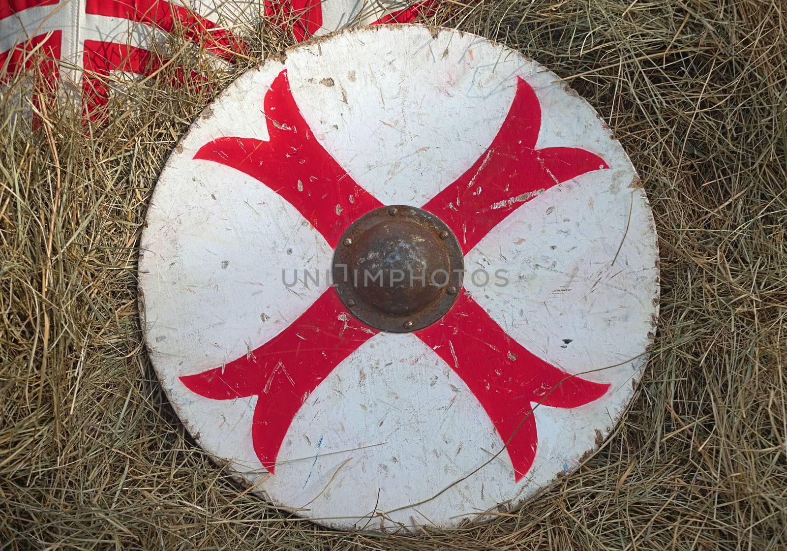 Medieval white with red cross wooden shield on hay by sheriffkule