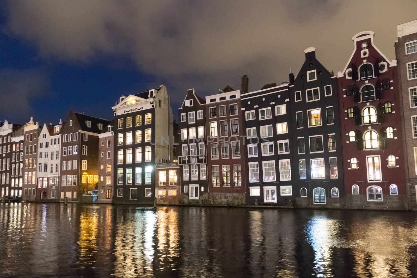 Amstedam, capital of Netherlands. Beautiful tranquil scene of city of Amsterdam at dusk. Bicycles along the street and on the bridge over the canal.
