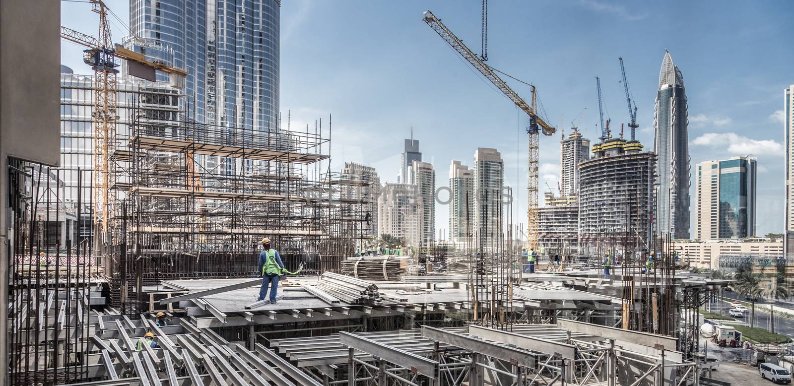 Laborers working on modern constraction site works in Dubai. Fast urban development consept.