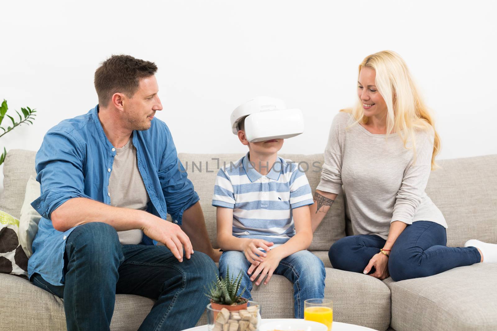 Happy family at home on living room sofa having fun playing games using virtual reality headset by kasto