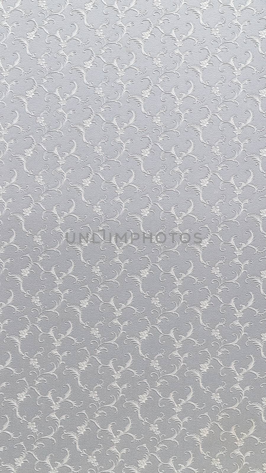 Embossed floral pattern on light gray paper. Textured paper with copy space. Motley gray-brown paper surface, texture closeup.