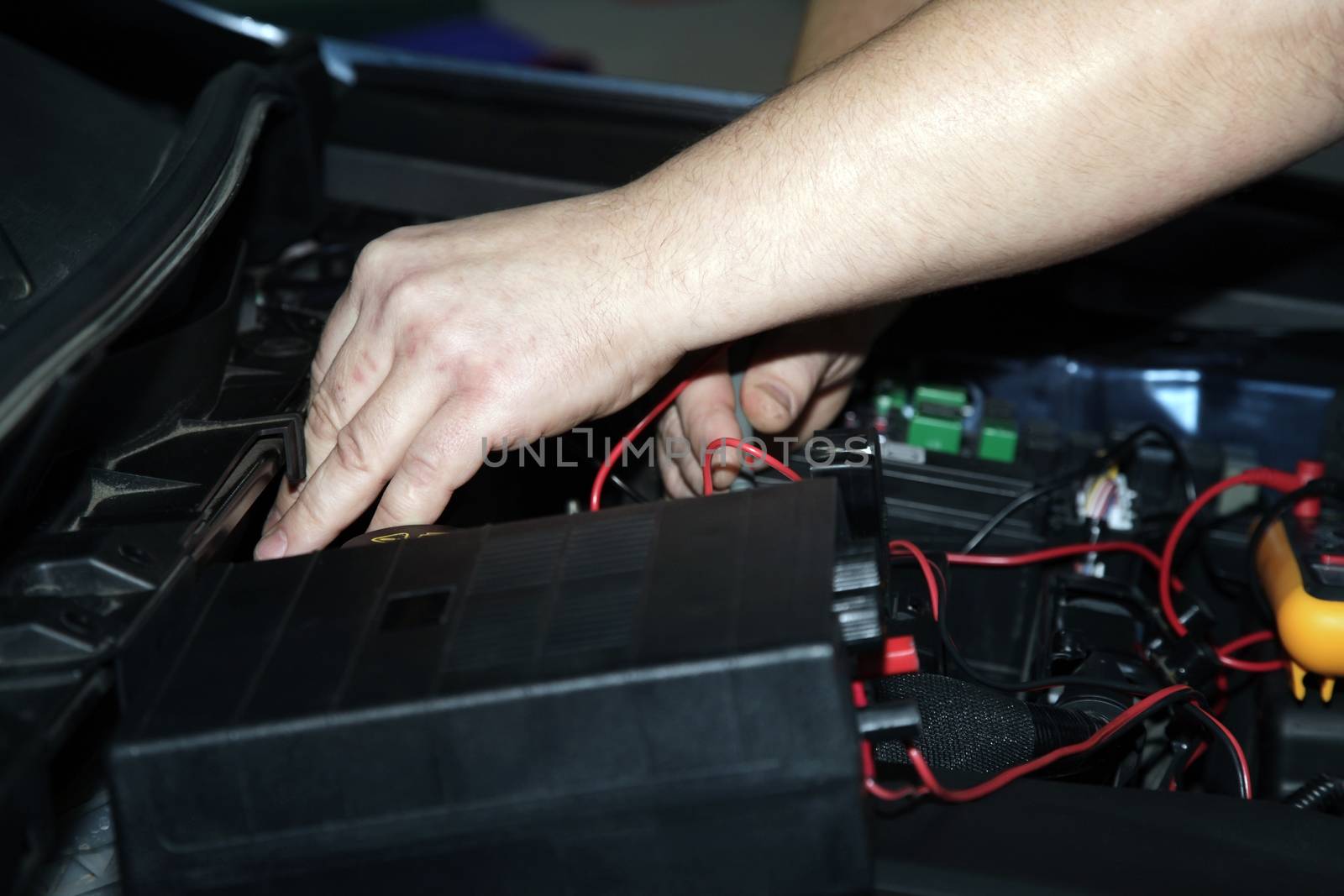 Male hands performing car repair with open hood