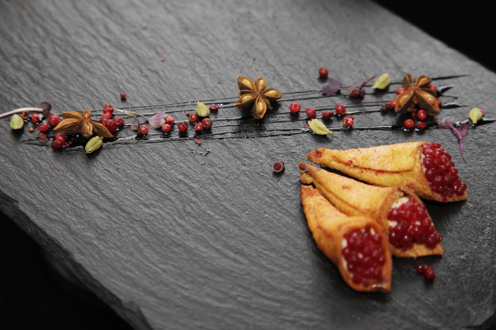 Rabbit pate in crispy horns decorated with spices on a black stone plate