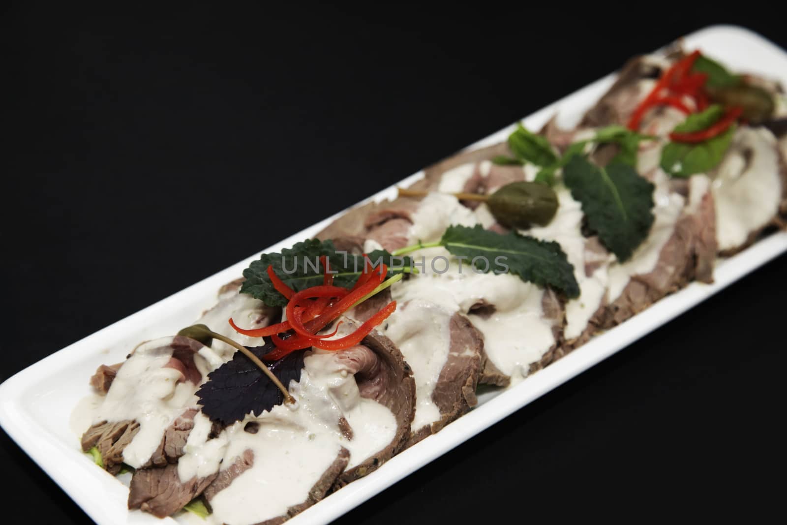 meat appetizer with cream sauce in a white rectangular plate by friday