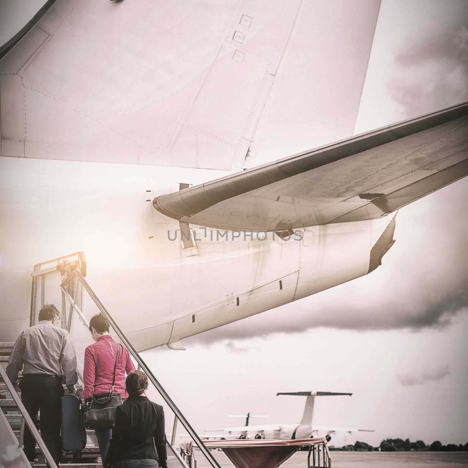 Rear view of people boarding in airplane at runway