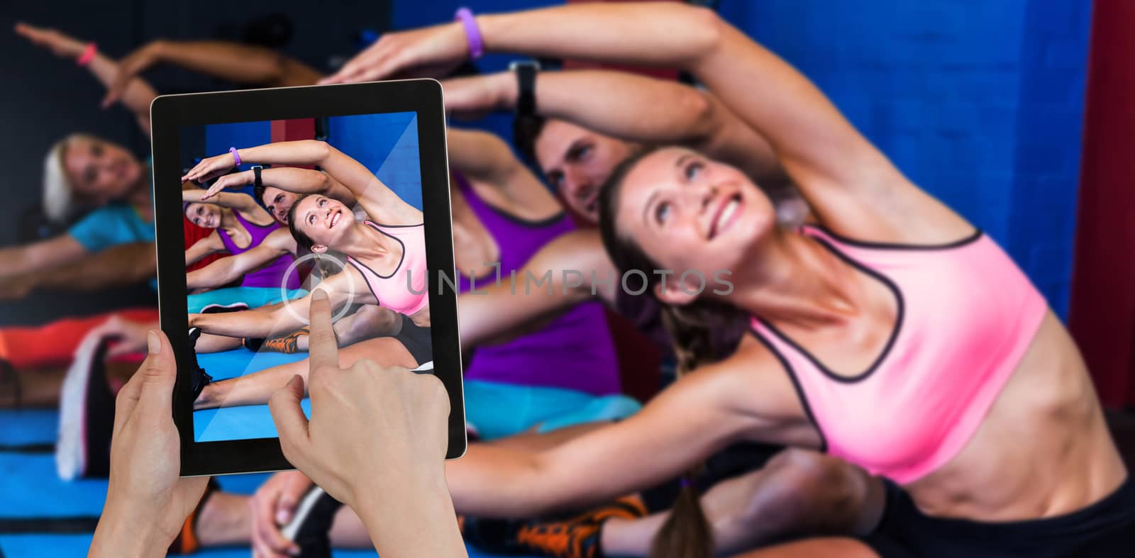 Hands touching digital tablet against white background against smiling people doing stretching exercise in gym