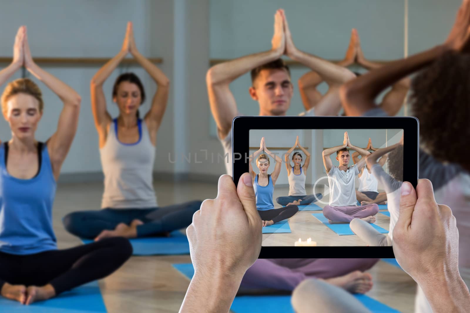 Cropped hand holding digital tablet against instructor taking yoga class