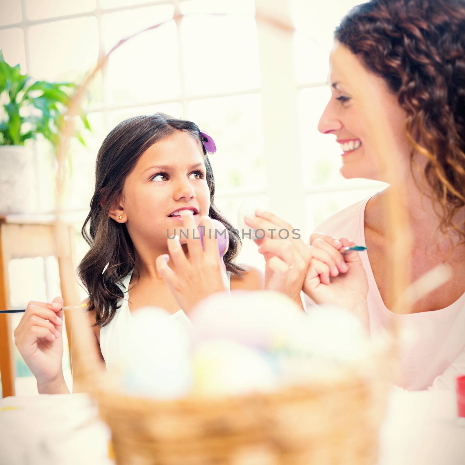 Happy mother and daughter painting easter eggs in the living room