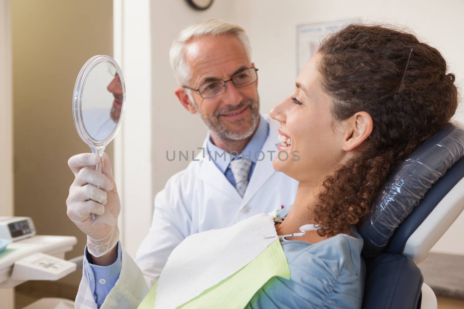 Patient admiring her new smile in the mirror at the dental clinic