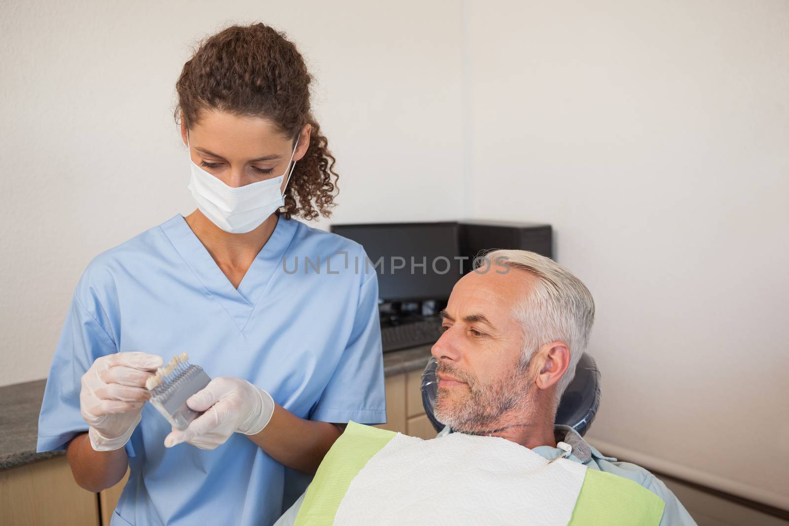 Dentist showing patient model of teeth by Wavebreakmedia