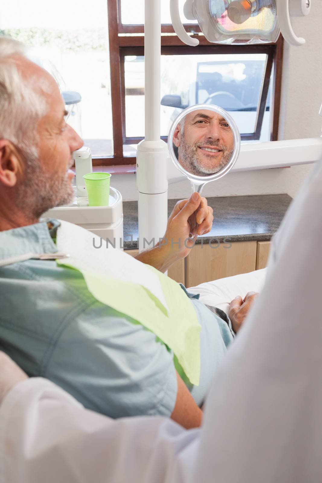 Patient admiring new smile in the mirror at the dental clinic