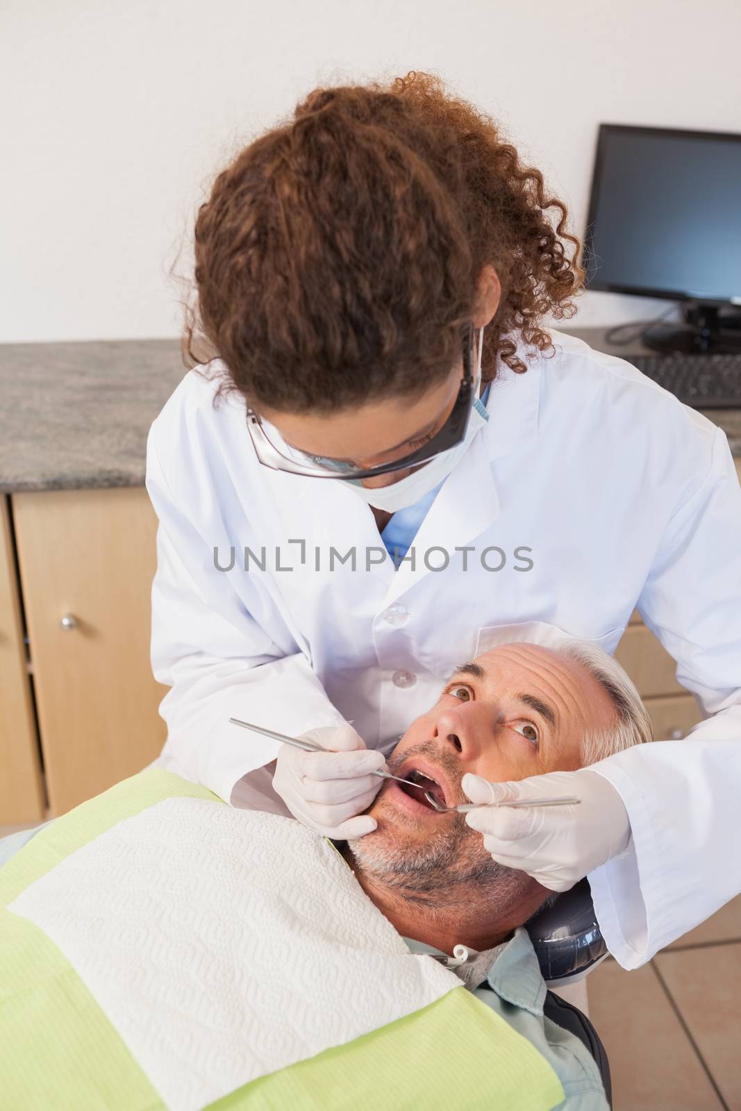 Dentist examining a patients teeth in the dentists chair at the dental clinic