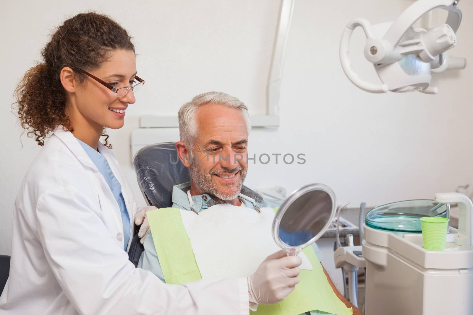 Dentist showing patient his new smile in the mirror by Wavebreakmedia