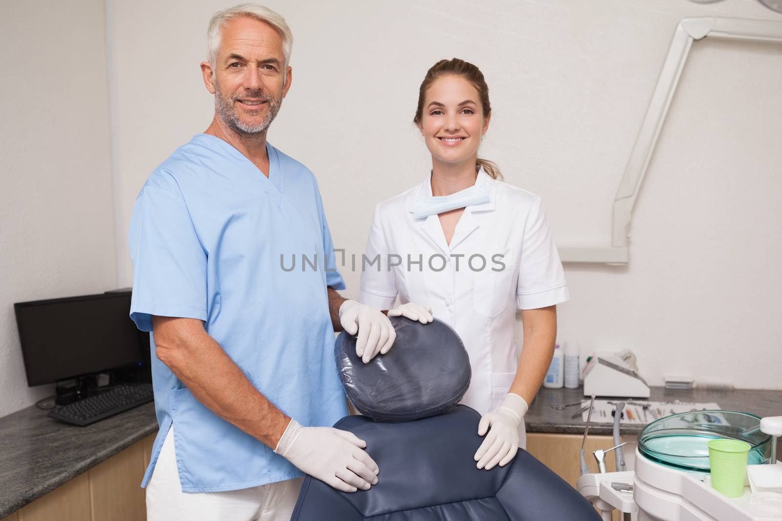 Dentist and assistant smiling at camera inviting you to the chair at the dental clinic