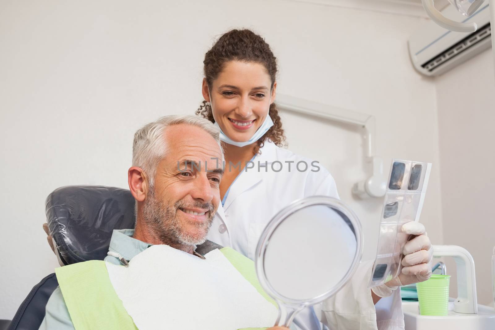 Patient admiring his new smile in the mirror at the dental clinic