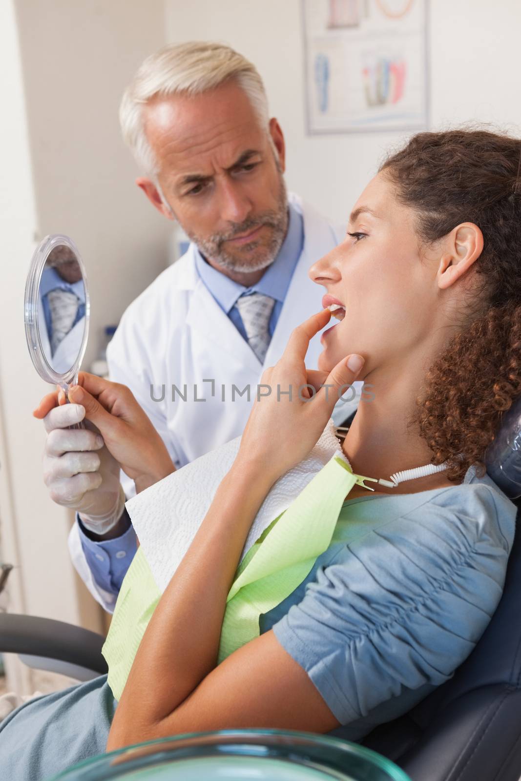 Patient showing dentist the problem in the mirror at the dental clinic