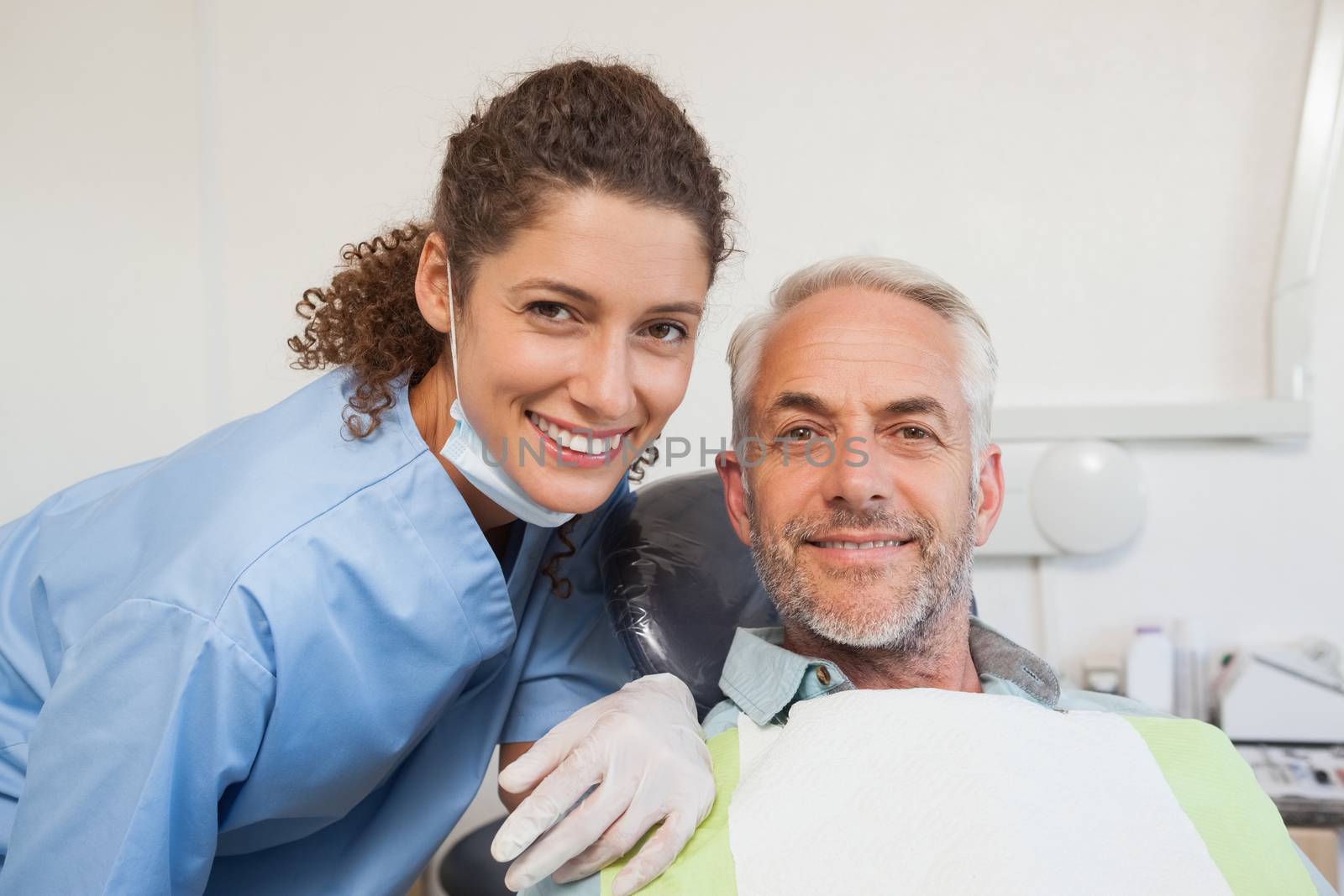 Dentist and patient smiling at camera at the dental clinic