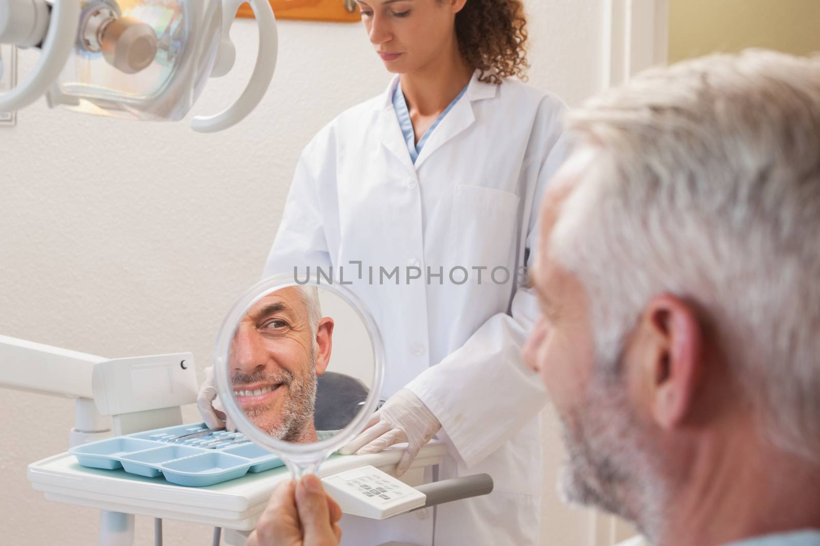 Patient admiring new smile in the mirror by Wavebreakmedia