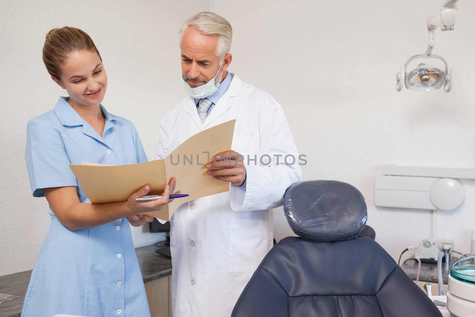 Dentist and assistant looking at file together at the dental clinic