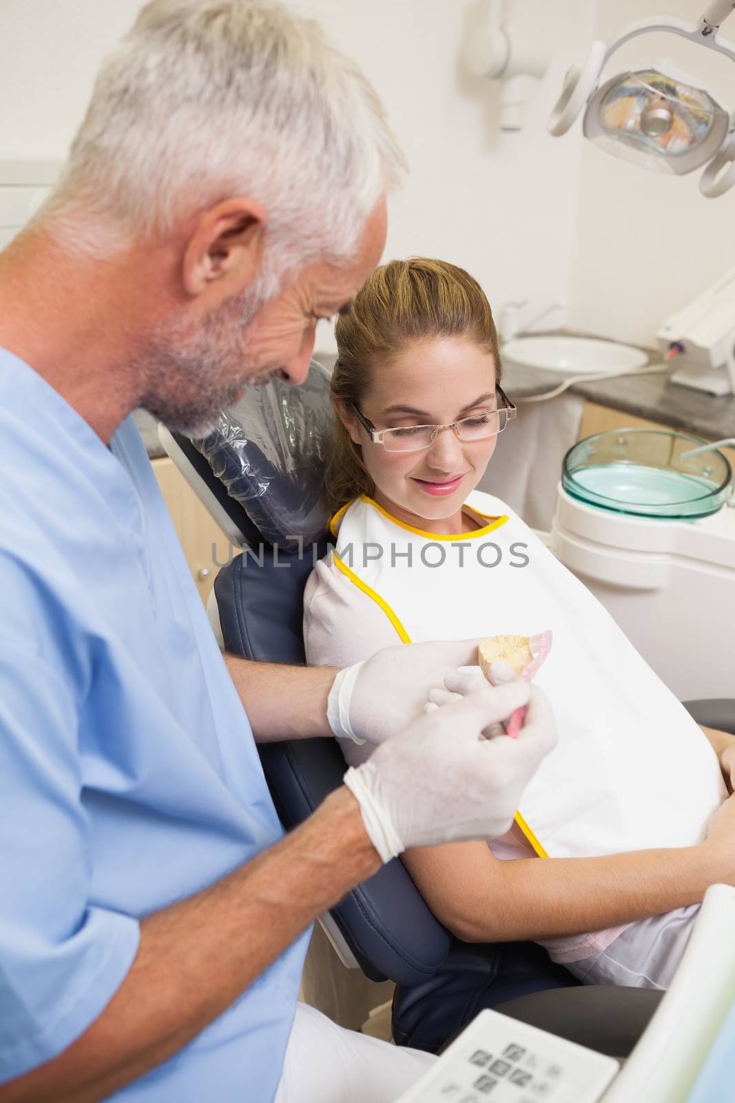 Dentist showing patient model of teeth at the dental clinic