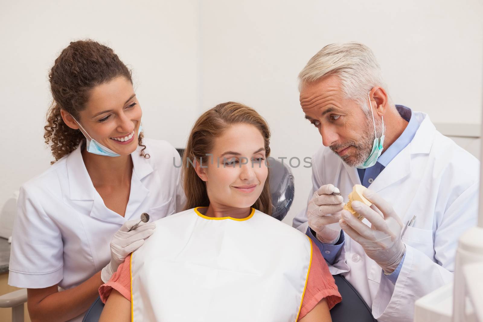 Dentist and assistant smiling with patient in chair by Wavebreakmedia