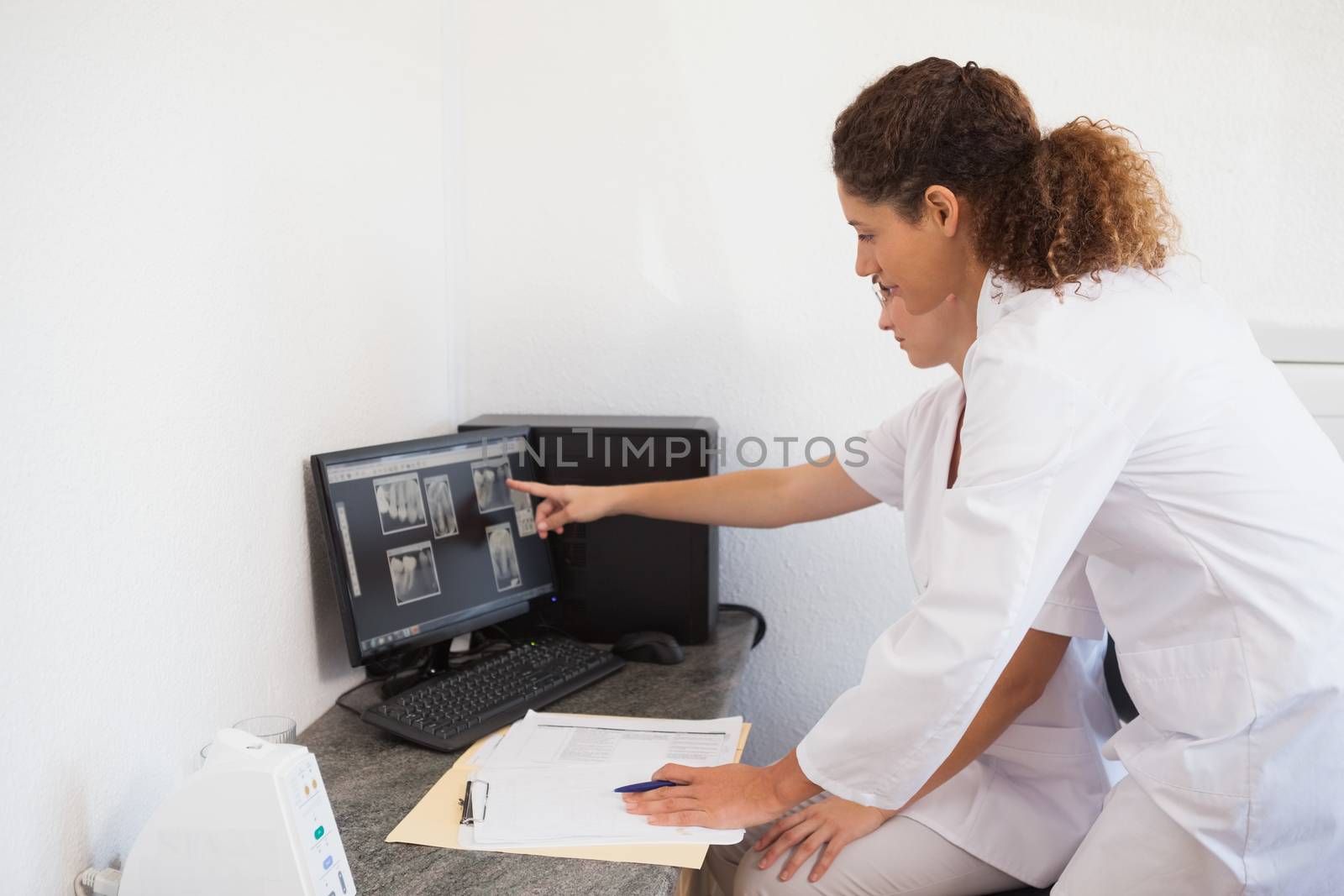 Dentist and assistant studying x-rays on computer by Wavebreakmedia