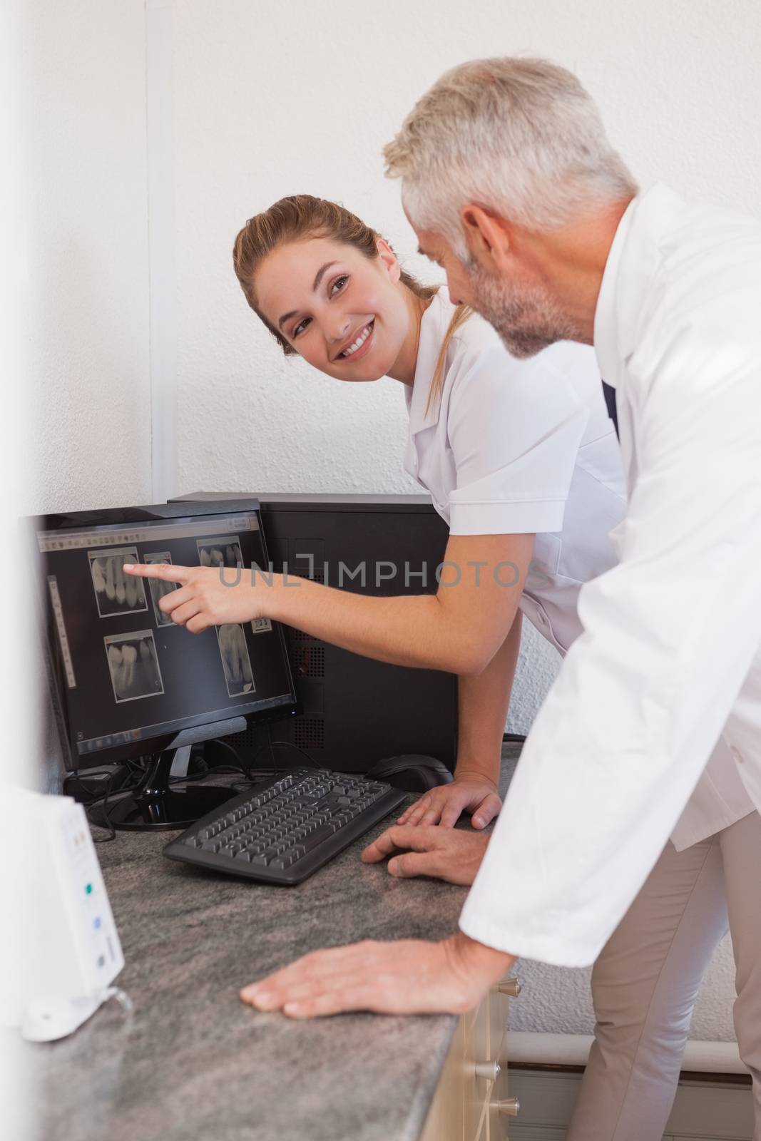 Dentist and assistant studying x-rays on computer by Wavebreakmedia