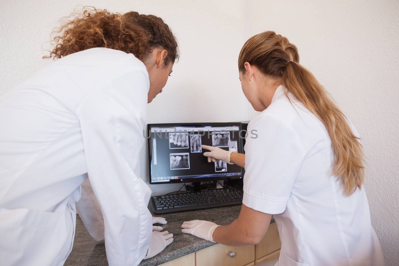 Dentist and assistant studying x-rays on computer at the dental clinic