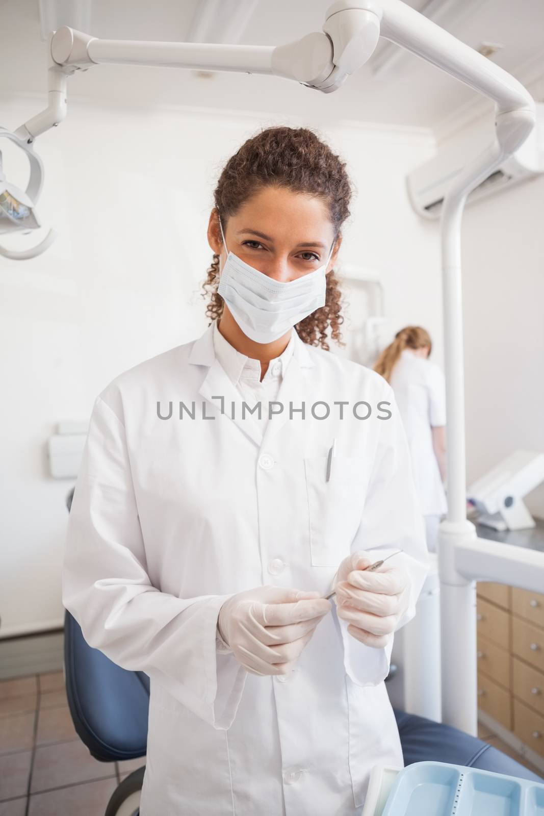 Dentist examining her tools on a tray looking at camera by Wavebreakmedia