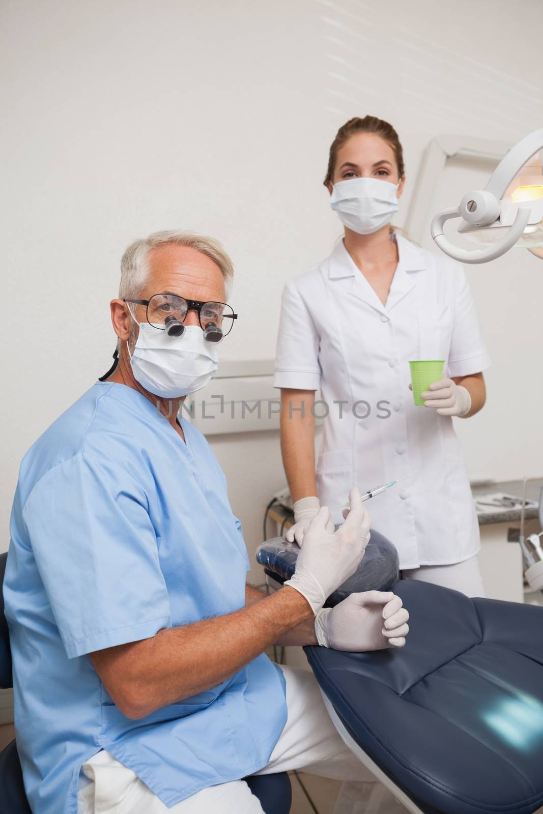 Dentist and assistant looking at camera by the chair by Wavebreakmedia