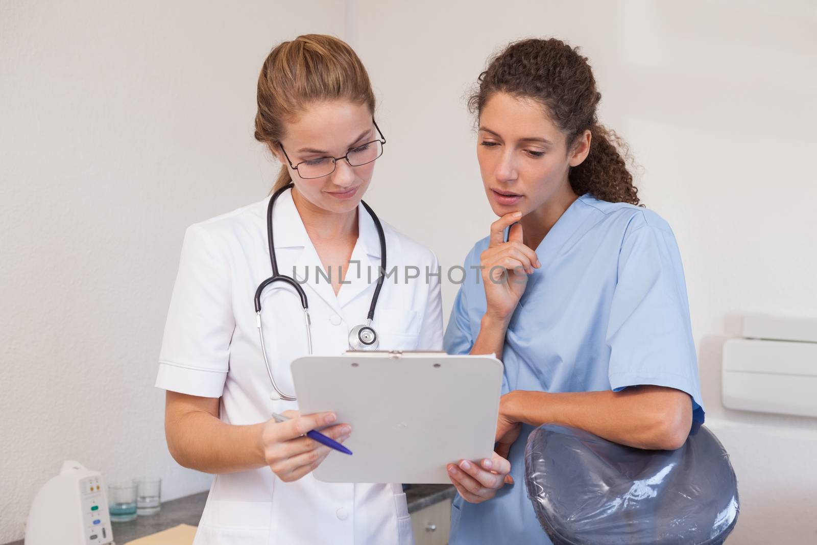 Dentist and dental assistant looking at clipboard at the dental clinic