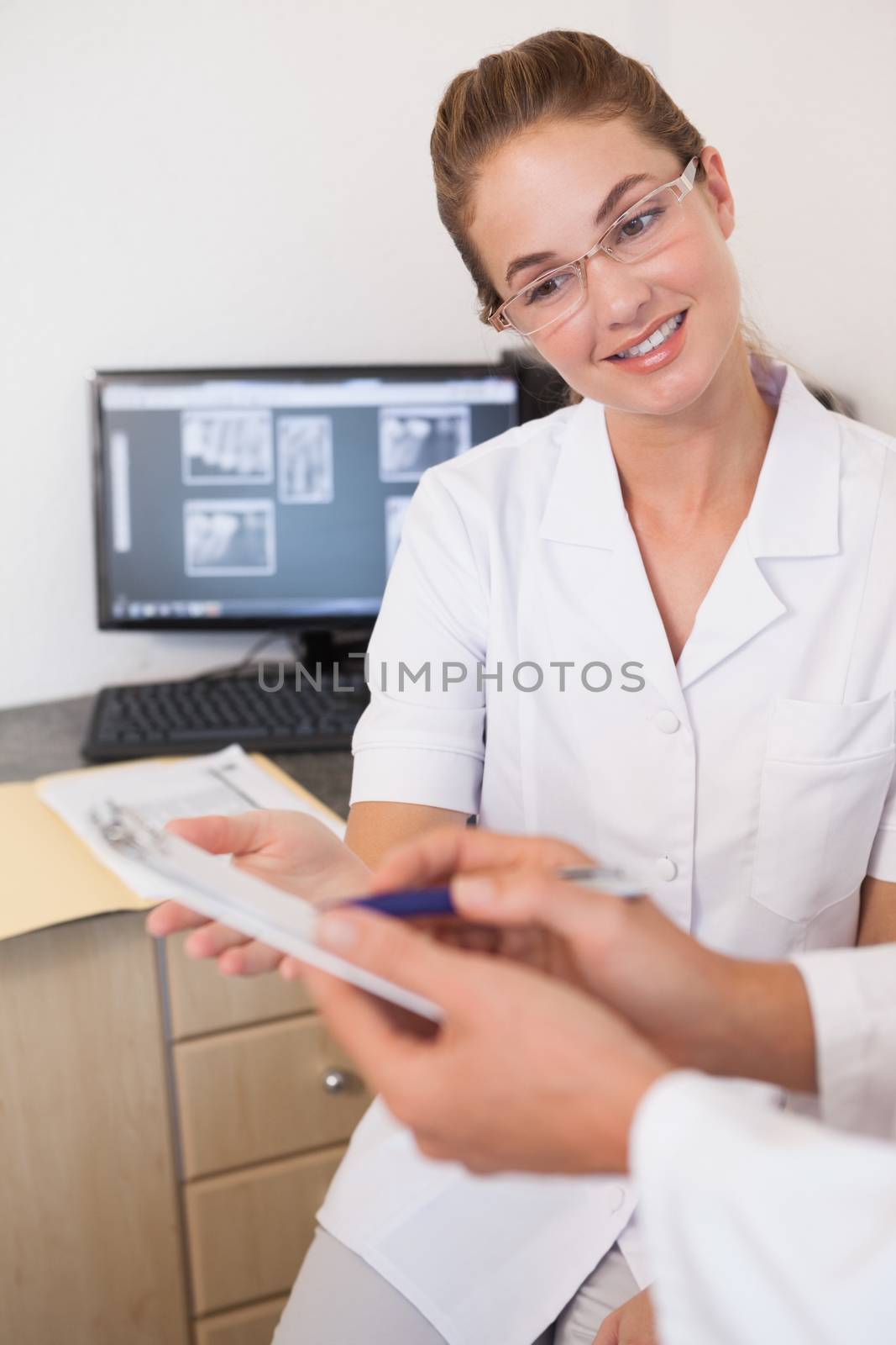 Dentist and assistant studying x-rays on computer at the dental clinic