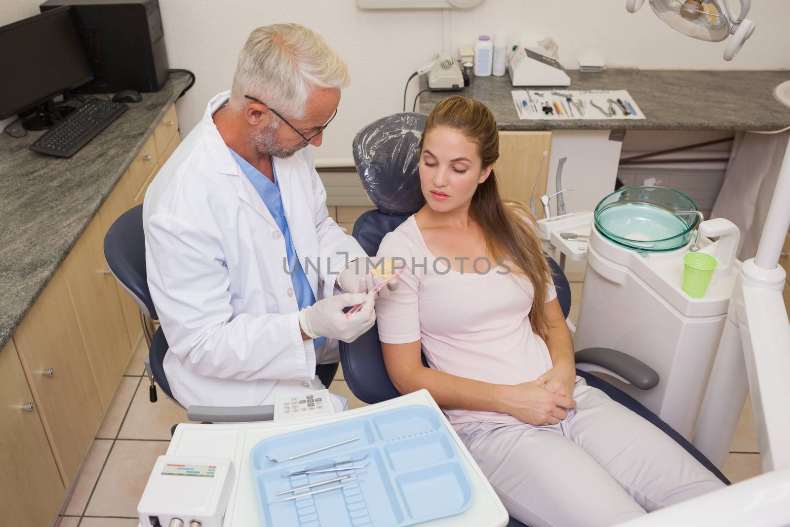 Dentist speaking with patient in the chair showing model of mouth at the dental clinic