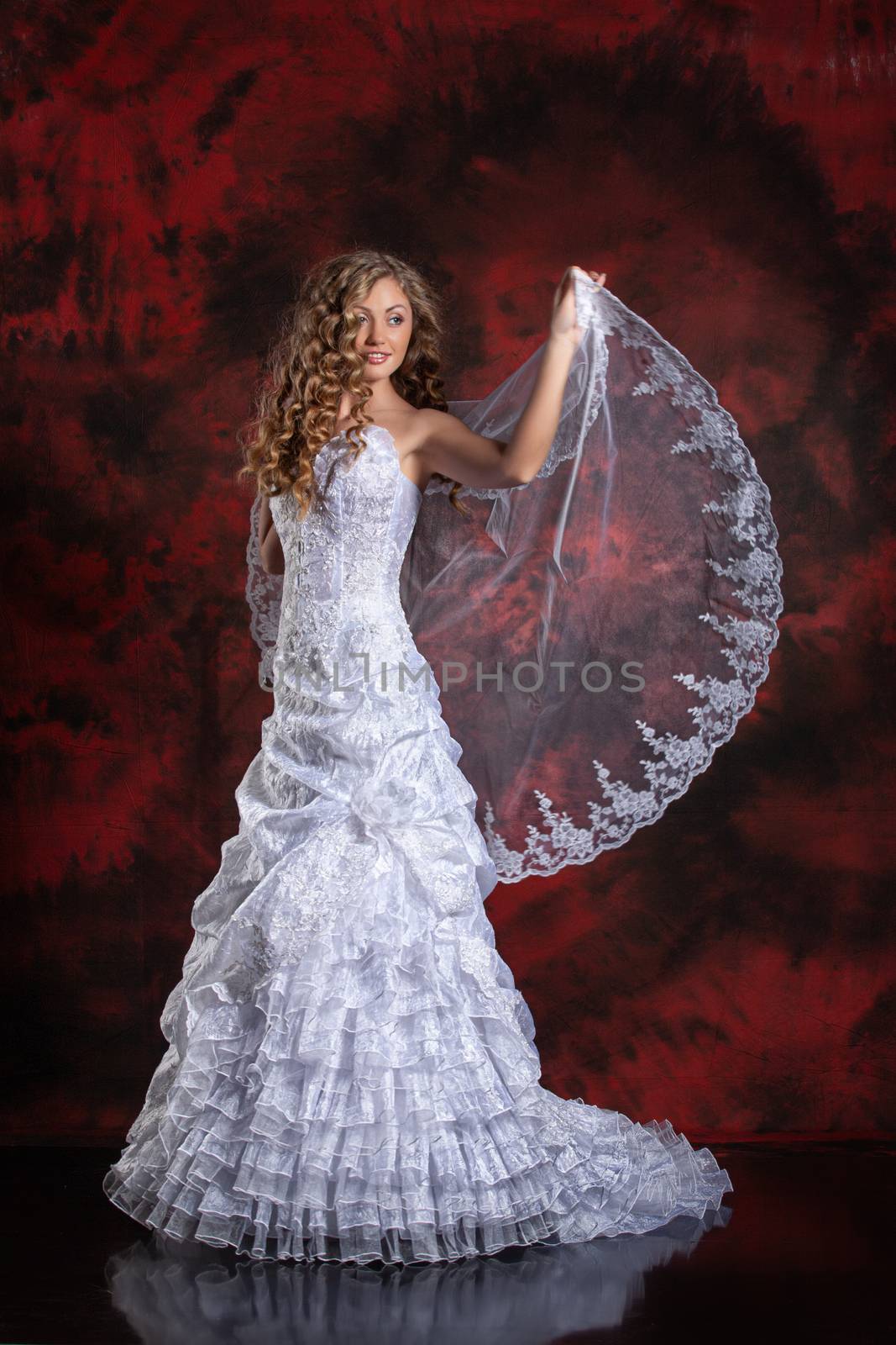 Young beautiful woman in a wedding dress on a studio background