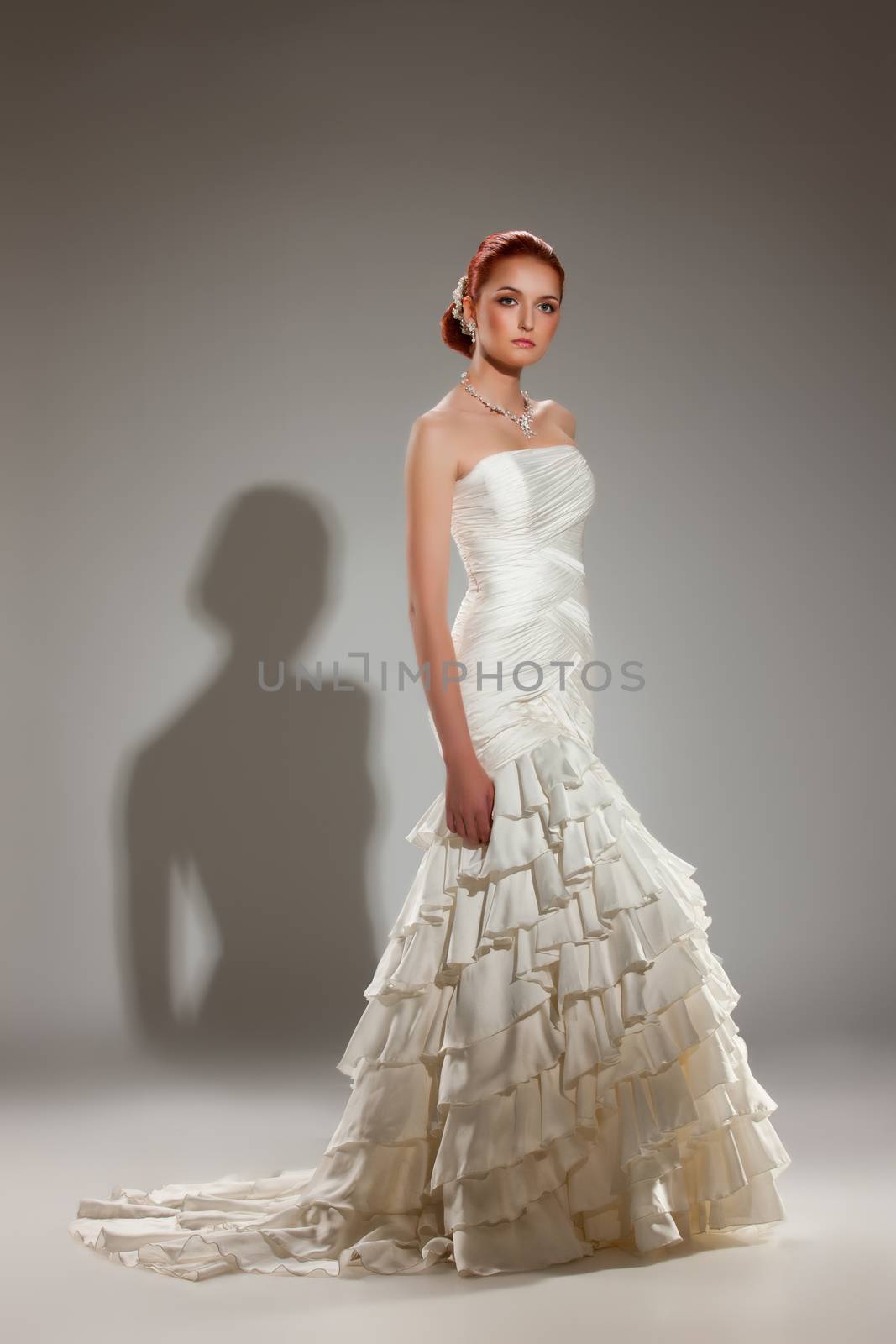 Young woman in a weddng dress on a studio background