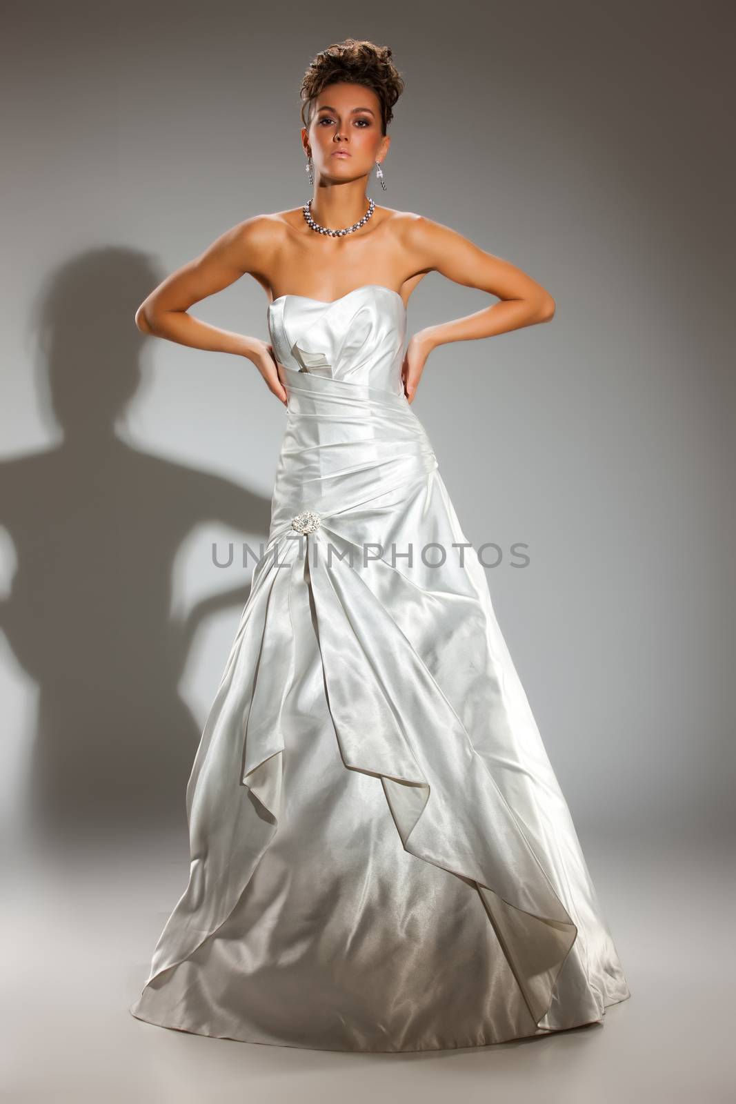 Young beautiful woman in a wedding dress on a studio background