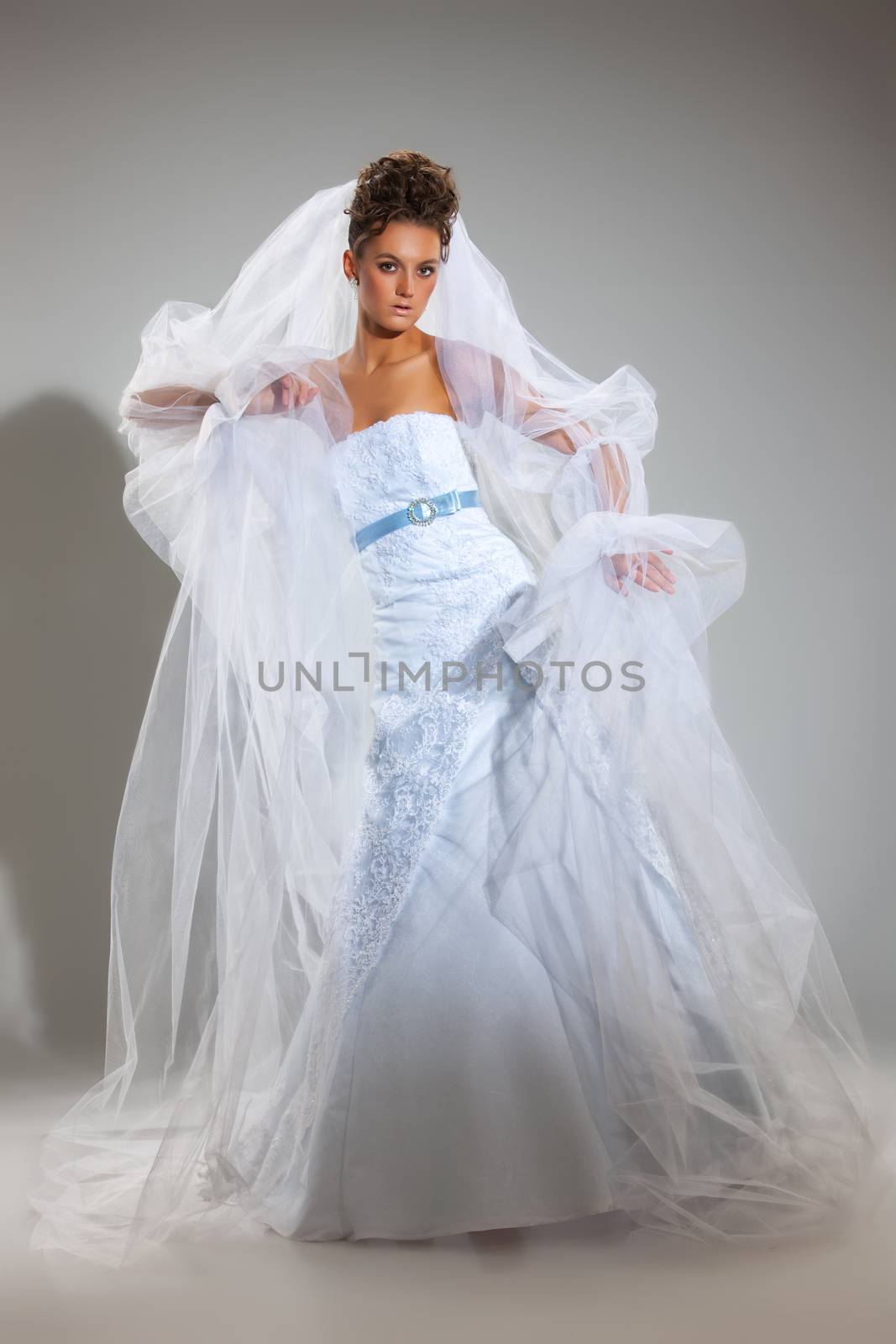 Young beautiful woman in a wedding dress on a studio background