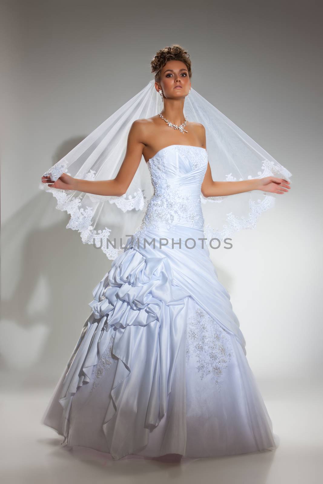 Young beautiful woman in a wedding dress on a studio background