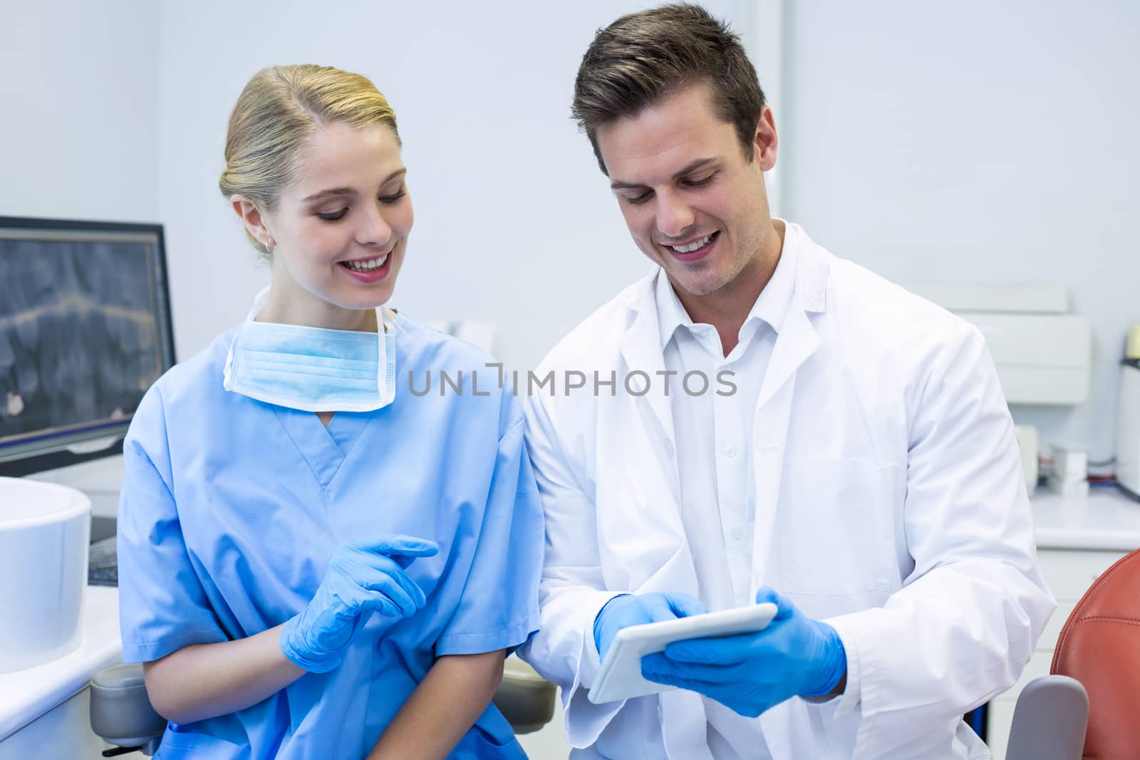 Happy dentist and nurse using digital tablet in clinic